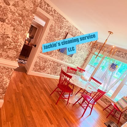 A clean dining room with red chairs, a round white table and shining hardwood floors