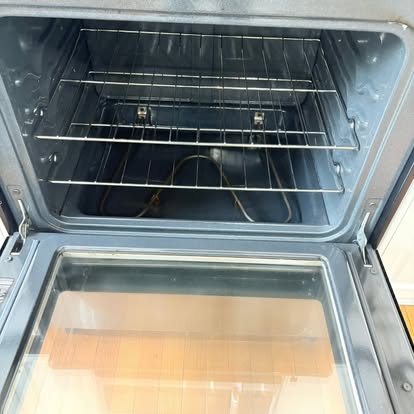 The inside of an oven wiped clean, with its racks in place and the door open
